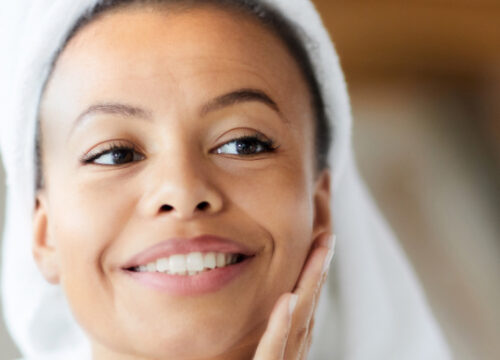 Photo of a smiling woman with a towel wrapped around her head after a shower